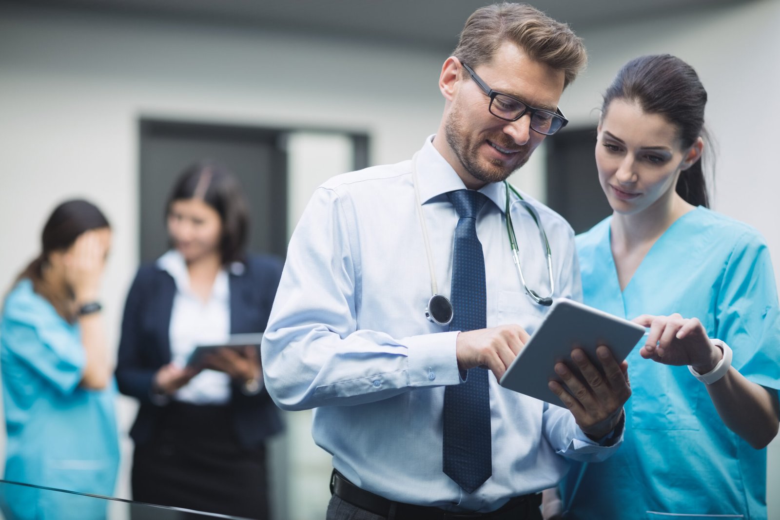 Doctor and nurse discussing over digital tablet in hospital corridor